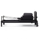 Pilates reformer aluminum total black, side view with sitting box